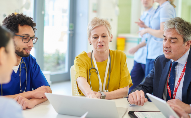 Female doctor and two male doctors looking at a laptop