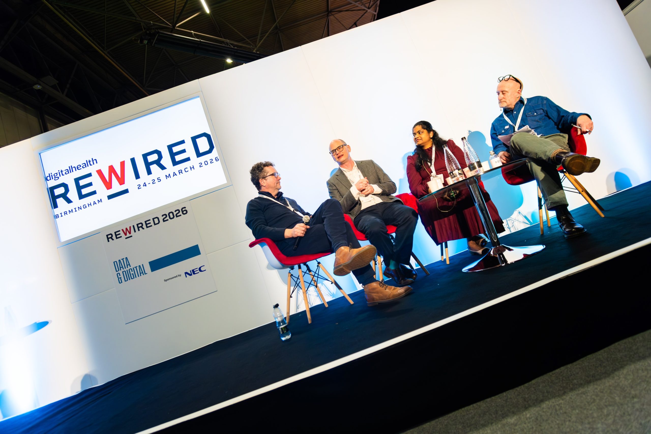 Jon Hoeksma, chief executive at Future Health Intelligence; Will Monaghan, group chief digital information officer at University Hospital Leicester NHS Trust; Kavitha Saravanakumar, interim chief information officer, NHS North West London; and Marc Farr, chief analytical officer at East Kent Hospitals University NHS Foundation Trust on the stage at Rewired 2026